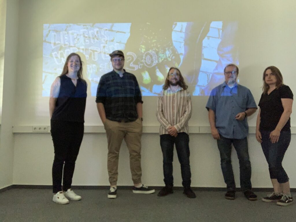 Gruppenfoto der pädagogischen Fachkräfte, die am Projekt Lebenswelten treffen sich 2.0 teilnehmen. Fünf Personen stehen vor dem Logo von dem Projekt.